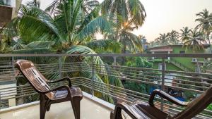 西奥利姆Poolside Paradise 1Bhk Luxury Apartment in Siolim.的两把椅子坐在棕榈树阳台