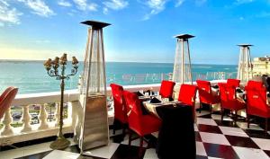 亚历山大Le Metropole Luxury Heritage Hotel Since 1902 by Paradise Inn Group的一间设有红色椅子的餐厅,享有海景