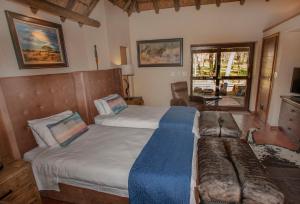 法尔瓦特Ilanga Safari Lodge - Welgevonden Game Reserve的一间带两张床和一张沙发的卧室
