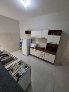 阿拉卡茹Casa 2/4 para temporada的厨房配有白色橱柜、炉灶和冰箱。