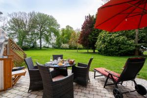 费马恩Fehmarn Mein Urlaub的庭院配有桌椅和红色遮阳伞