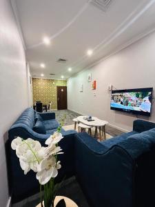 科威特De Iris Regency Fahaheel的客厅配有蓝色的沙发和平面电视。