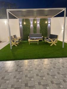 Qufārشاليه راقي بمسطحات خضراء وغرفة نوم的凉亭,草地上设有长椅和桌子