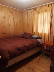 普孔Cabaña Agradable的一间卧室配有一张带木墙和窗户的床。