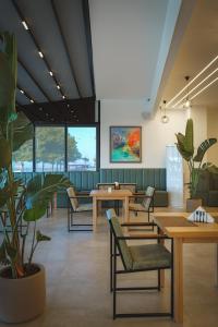 伏罗拉Sea & Sand Hotel的一间设有桌椅和植物的等候室