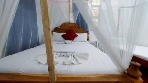 江比阿Jacob's Inn Jambiani的卧室配有带白色床单的天蓬床