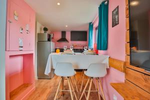 Clermont-CréansCHALET CARAIBES SPA Privatif的厨房设有粉红色的墙壁和白色的桌椅
