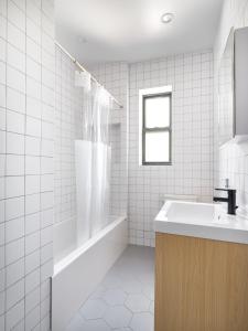 布鲁克林Modern Three Bedroom Brooklyn Condo-Hotel的白色瓷砖浴室设有水槽和浴缸