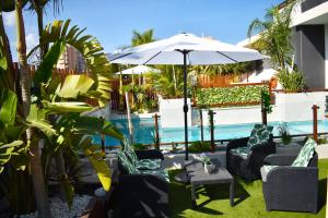 Playa ParaisoAlaïa Apartamentos的一个带椅子和遮阳伞的庭院和一个游泳池