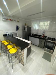 大普拉亚Casa de Praia - Distância de 100 metros的厨房配有柜台和黄色椅子