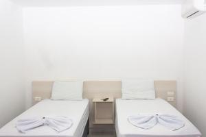 Palmeira dos ÍndiosHotel Grandville II的白色墙壁客房的两张床