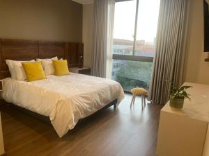 科恰班巴Gratus的一间卧室配有一张带黄色枕头的床和一扇窗户