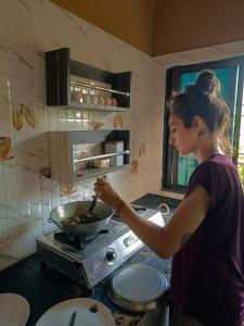 菩提伽耶Hostel Osara的女人在厨房里挑一碗食物