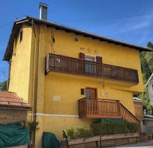 皮耶韦迪卡多雷In cima alla contrada的黄色房子的一侧设有阳台