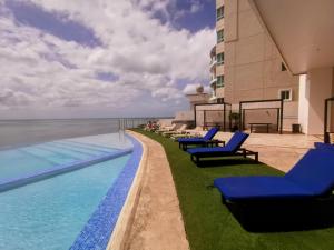 巴拿马城Punta Pacífica Oceanfront apartment的一座带蓝色躺椅的游泳池,位于大楼旁
