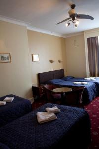 伦敦玫瑰园酒店的酒店客房设有三张床和一张桌子