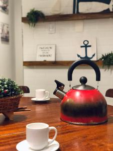 尼西亚弗洛雷斯塔Duplex Beira-mar em condomínio / Búzios-RN的茶壶,坐在木桌旁,有2杯