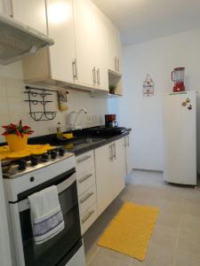 伯迪亚哥Bate & Volta - Apartamentos com 2 quartos próximo ao SESC Bertioga的厨房配有白色橱柜、炉灶和冰箱。