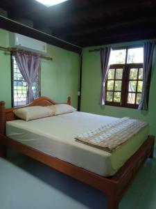 Ban Khlong Bang KhrokThe Orange House Thailand - Baan P'Nae Homestay的卧室设有一张大床,设有两个窗户