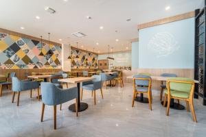 龙目岛库塔MONTANA @OCEANSIDE MANDALIKA的餐厅设有桌椅和投影屏幕