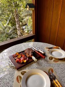 加斯帕Casa de campo com cachoeira no quintal的桌子上放着一盘食物的桌子