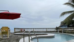 克里比Hotel les Polygones Kribi的一个带红色遮阳伞和桌椅的游泳池