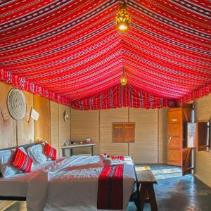 Al QābilSAMA Al Areesh Camp的一间设有红色天篷床的客房