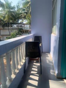 马焦茹达Shangrila by Craftels的阳台配有两把椅子、墙壁和棕榈树