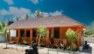 龙目岛库塔Mandalika Queen Hostel的小木屋设有门廊和一些棕榈树