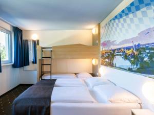 慕尼黑北慕尼黑城市住宿加早餐旅馆的一间卧室设有三张床,墙上挂着一幅画