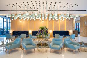 马斯喀特Maani Muscat Hotel & Suites的大堂设有椅子、桌子和吊灯。
