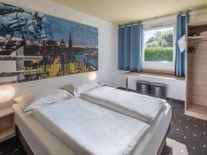 维尔塞伦B&B HOTEL Aachen-Würselen的一间卧室设有一张大床和一个窗户。