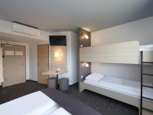 舍讷费尔德柏林机场住宿加早餐酒店的一间卧室配有两张双层床和一张书桌
