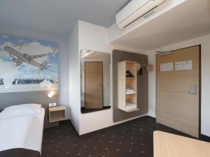 舍讷费尔德柏林机场住宿加早餐酒店的一间房间,卧室墙上挂有飞机绘画