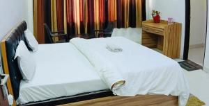 PrayagrajMauji's Villa Hotel & Guest House的一间卧室配有两张白色的床和一张书桌