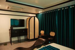 Bắc GiangSky Hotel的一间卧室配有床、电视和绿色窗帘