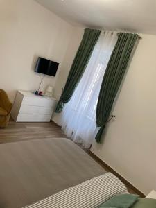 亚历山德里亚Residence savonarola的一间卧室设有床铺和一个带绿色窗帘的窗户。