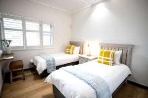 赫曼努斯Bayview 303的一间卧室配有两张带黄色和蓝色枕头的床