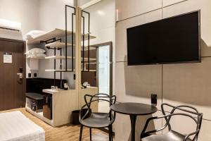 伊塔佩马Tri Hotel Premium Itapema的客厅配有桌椅和电视。