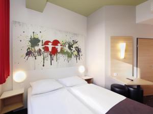 柏林B&B HOTEL Berlin-Potsdamer Platz的酒店客房设有一张床,墙上挂有绘画作品