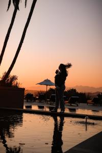 克尼斯纳Pezula Nature Retreat的站在游泳池边的女人,背着日落