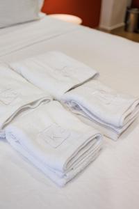 卡拉马塔K2 Suites Kalamata的一组白色毛巾堆在床上