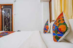 浦那FabHotel Lake View的一间卧室配有两张带色彩缤纷枕头的床。