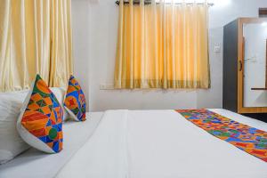 浦那FabHotel Lake View的卧室配有白色的床和色彩缤纷的枕头