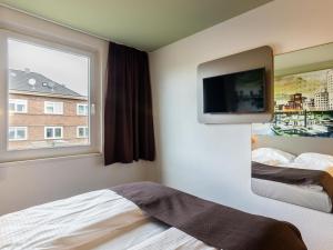 杜塞尔多夫B&B Hotel Düsseldorf City-Süd的一间卧室设有一张床、一台电视和一个窗口。