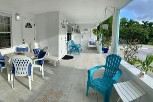 西湾SUITE 1, Blue Pavilion - Beach, Airport Taxi, Concierge, Island Retro Chic的露台设有蓝色椅子和门廊上的桌子