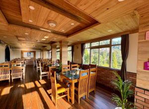 大吉岭Darjeeling Hillside Inn的用餐室配有木桌和椅子