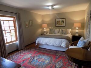巴里代尔Barrydale Karoo Lodge - Boutique Hotel的一间卧室配有一张床、一张桌子和一个窗户。