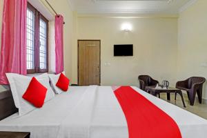 德拉敦Balindira Guest House的卧室配有带红色枕头的大型白色床