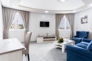 盖尼特拉Hotel Mamora Kénitra的客厅配有2把蓝色椅子和电视